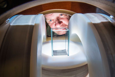 Sandia National Laboratories researcher Jim Martin peers between specially built magnets to watch patterns form in a liquid inside a 3-centimeter (1.2-inch) container. He and Sandia doctoral researcher Kyle Solis have discovered how to harness magnetic fields to create vigorous, organized fluid flows in particle suspensions. (Photo by Randy Montoya) 